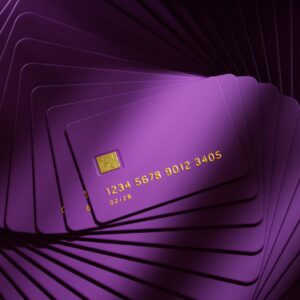 A stack of purple credit cards with gold numbers, letters, and chip.