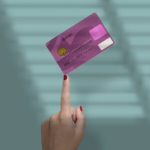 A finger poking and holding up a purple credit card against a blue background