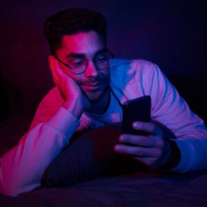 A man in a dark room looking at his phone