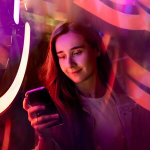 A woman looking at her phone in a purple and orange abstract background