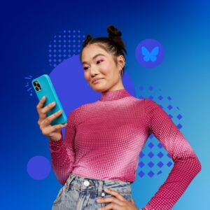 A young woman in a pink top smiling at her phone. The blue background has the Bluesky Social logo in a bubble.